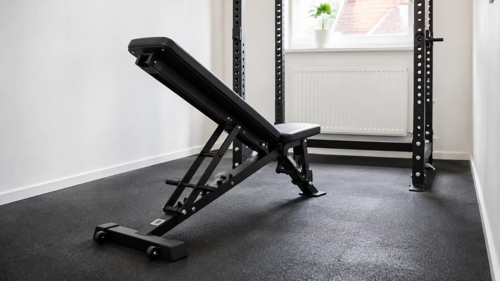 Zwarte verstelbare trainingsbank voor een rack in een smalle lichte thuissportruimte